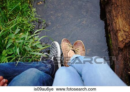 Stock Image - Couple sitting outdoors, low section. Fotosearch