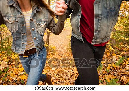Stock Photography - Cropped shot of romantic young couple running through autumn forest. Fotosearch