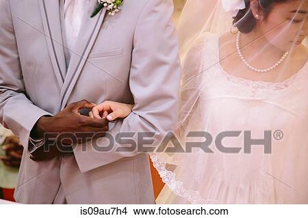Cropped view of bride wearing veil and bridegroom holding hands View Large Photo Image Picture - Cropped view of bride wearing veil and bridegroom holding hands. Fotosearch