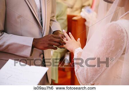 Cropped view of bridegroom putting ring on brides finger at wedding ceremony View Large Photo Image Stock Photograph - Cropped view of bridegroom putting ring on brides finger at wedding ceremony. Fotosearch