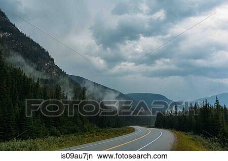 Picture - Diminishing perspective of empty open road and misty mountain range, Moraine lake, Banff National Park, Alberta Canada. Fotosearch