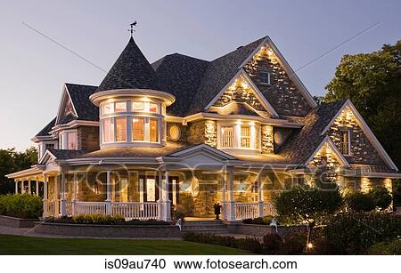 Stock Image - Elegant grey stone house with white trim and blue roof at dusk in summer, Quebec, Canada. Fotosearch