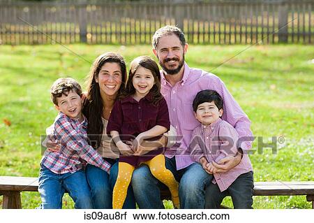 Family sitting on bench together looking at camera smiling View Large Photo Image Stock Image - Family sitting on bench together looking at camera smiling. Fotosearch