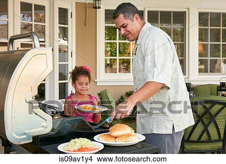 Picture - Father and daughter on patio grilling barbecue food smiling. Fotosearch