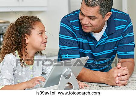 Stock Image - Father and daughter using digital tablet face to face smiling. Fotosearch