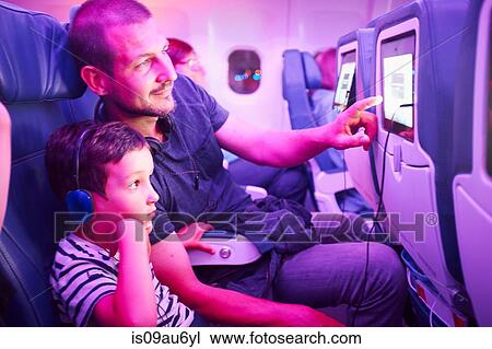 Father and son sitting in aeroplane, looking at in-flight TV screen View Large Photo Image Stock Image - Father and son sitting in aeroplane, looking at in-flight TV screen. Fotosearch