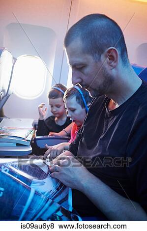 Stock Photo - Father and two sons sitting in aeroplane. Fotosearch