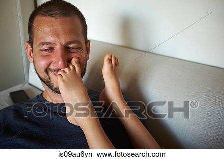 Father sitting on sofa, son's bare feet touching his face View Large Photo Image Picture - Father sitting on sofa, son's bare feet touching his face. Fotosearch