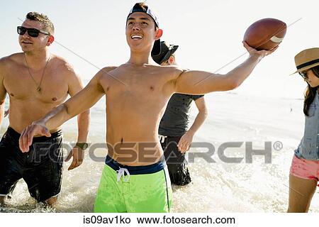 Four adult friends playing American football in sea at Newport Beach, California, USA View Large Photo Image Picture - Four adult friends playing American football in sea at Newport Beach, California, USA. Fotosearch