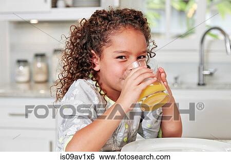 Girl at kitchen counter drinking orange juice looking at camera View Large Photo Image Stock Photograph - Girl at kitchen counter drinking orange juice looking at camera. Fotosearch
