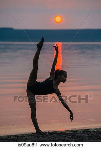 Girl by ocean at sunset on one leg, bending forward arm and leg raised View Large Photo Image Stock Image - Girl by ocean at sunset on one leg, bending forward arm and leg raised. Fotosearch