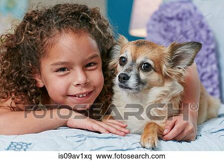 Girl lying on bed arm around dog, looking at camera smiling View Large Photo Image Stock Photography - Girl lying on bed arm around dog, looking at camera smiling. Fotosearch