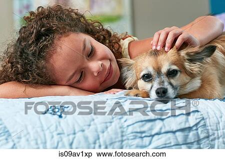 Girl lying on bed stroking dog View Large Photo Image Stock Photography - Girl lying on bed stroking dog. Fotosearch