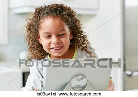 Stock Image - Girl using digital tablet looking down smiling. Fotosearch