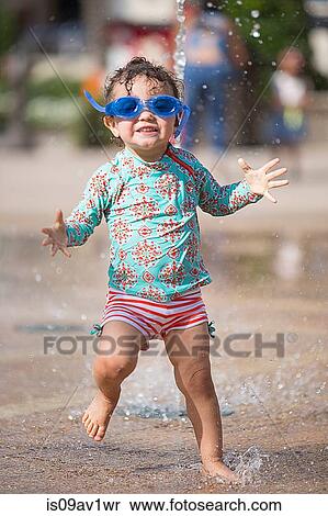 Girl wearing swimming goggles playing in water fountain, looking at camera smiling View Large Photo Image Stock Photography - Girl wearing swimming goggles playing in water fountain, looking at camera smiling. Fotosearch