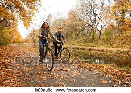 Happy young couple cycling along riverside in autumn View Large Photo Image Stock Image - Happy young couple cycling along riverside in autumn. Fotosearch