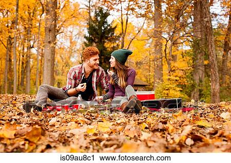 Stock Image - Happy young couple having picnic in autumn forest. Fotosearch