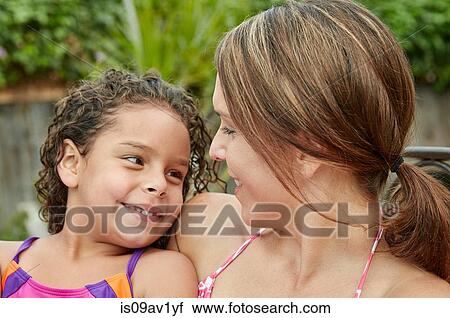 Stock Image - Head and shoulders of mother and daughter wearing swimwear face to face smiling. Fotosearch