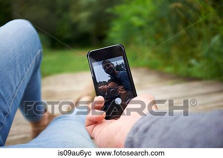 Heterosexual couple sitting outdoors, using smartphone, low section View Large Photo Image Stock Image - Heterosexual couple sitting outdoors, using smartphone, low section. Fotosearch