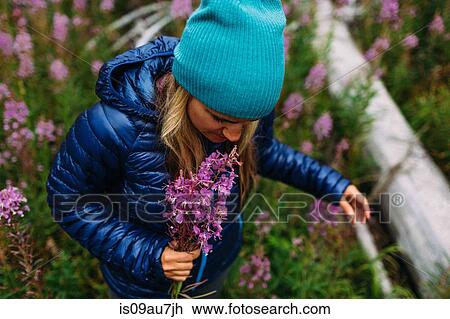 High angle view of mid adult woman wearing padded coat and knit hat holding wildflowers, Moraine lake, Banff National Park, Alberta Canada View Large Photo Image Stock Image - High angle view of mid adult woman wearing padded coat and knit hat holding wildflowers, Moraine lake, Banff National Park, Alberta Canada. Fotosearch