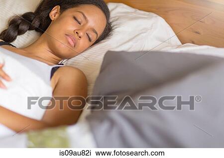 High angle view of young woman lying on back in bed eyes closed sleeping View Large Photo Image Stock Image - High angle view of young woman lying on back in bed eyes closed sleeping. Fotosearch