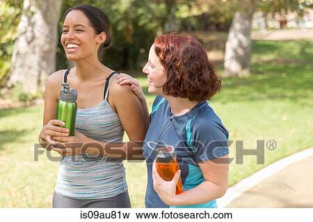 High angle view of young women out walking wearing sports clothing carrying water bottles smiling View Large Photo Image Stock Photo - High angle view of young women out walking wearing sports clothing carrying water bottles smiling. Fotosearch