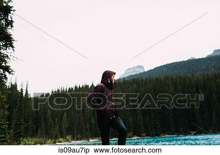 Low angle view of mid adult man in waterproof coat by Moraine lake, hands in pockets looking away, Banff National Park, Alberta Canada View Large Photo Image Stock Photography - Low angle view of mid adult man in waterproof coat by Moraine lake, hands in pockets looking away, Banff National Park, Alberta Canada. Fotosearch