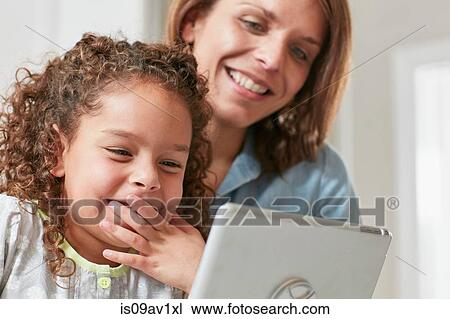 Low angle view of mother and daughter using digital tablet, hand over mouth smiling View Large Photo Image Stock Image - Low angle view of mother and daughter using digital tablet, hand over mouth smiling. Fotosearch