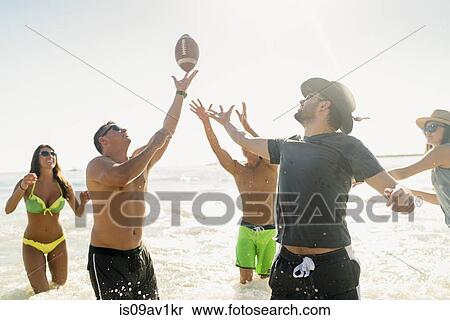 Male and female adult friends playing American football in sea at Newport Beach, California, USA View Large Photo Image Stock Photography - Male and female adult friends playing American football in sea at Newport Beach, California, USA. Fotosearch