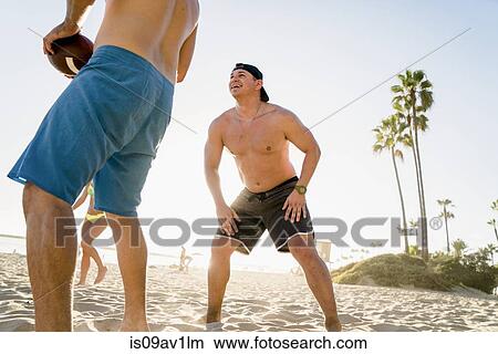 Male and female friends playing American football on Newport Beach, California, USA View Large Photo Image Picture - Male and female friends playing American football on Newport Beach, California, USA. Fotosearch