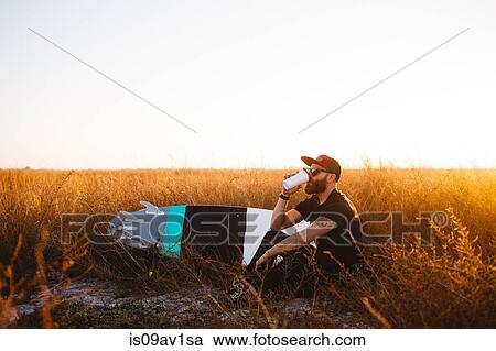 Male surfer drinking coffee in field of long grass at sunset, San Luis Obispo, California, USA View Large Photo Image Stock Image - Male surfer drinking coffee in field of long grass at sunset, San Luis Obispo, California, USA. Fotosearch