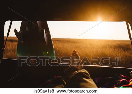 Stock Photo - Male surfer with bare feet up in back of jeep at sunset, San Luis Obispo, California, USA. Fotosearch