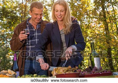 Mature couple carving roast chicken at garden dinner party View Large Photo Image Stock Photo - Mature couple carving roast chicken at garden dinner party. Fotosearch
