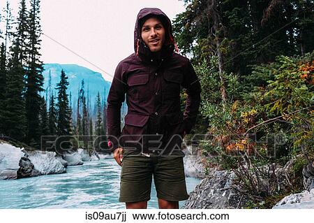 Mid adult man by river wearing hooded waterproof coat looking at camera smiling, Moraine lake, Banff National Park, Alberta Canada View Large Photo Image Stock Image - Mid adult man by river wearing hooded waterproof coat looking at camera smiling, Moraine lake, Banff National Park, Alberta Canada. Fotosearch