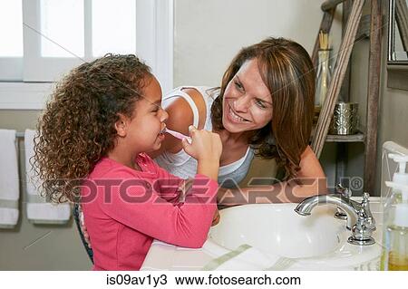 Mother and daughter in bathroom at sink brushing teeth face to face smiling View Large Photo Image Stock Image - Mother and daughter in bathroom at sink brushing teeth face to face smiling. Fotosearch