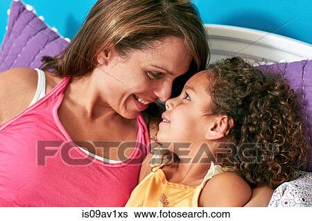 Stock Photograph - Mother and daughter in bed nose to nose smiling. Fotosearch