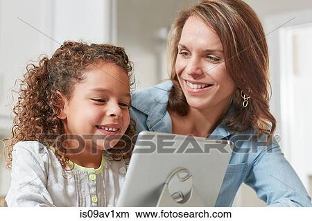 Mother and daughter using digital tablet, smiling View Large Photo Image Picture - Mother and daughter using digital tablet, smiling. Fotosearch