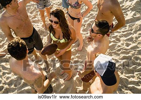 Stock Photography - Overhead view of adult friends with American football ball on Newport Beach, California, USA. Fotosearch