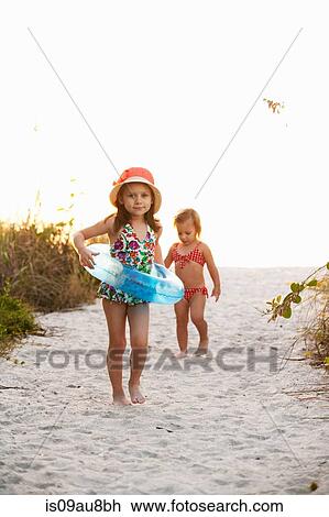 Stock Image - Portrait of girl and sister playing at beach, Sanibel, Florida, USA. Fotosearch