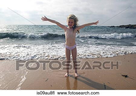 Stock Image - Portrait of girl with arms open on beach at Sardinia, Italy. Fotosearch