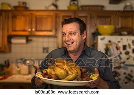 Portrait of mature man holding roast chicken dinner in kitchen View Large Photo Image Stock Photography - Portrait of mature man holding roast chicken dinner in kitchen. Fotosearch