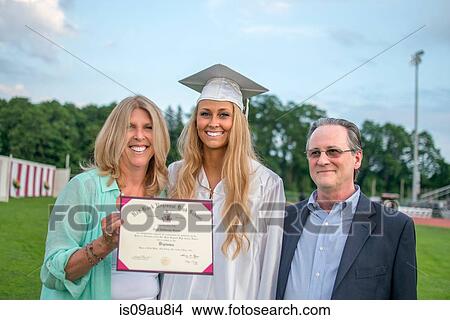 Portrait of young female graduate with parents at graduation ceremony View Large Photo Image Picture - Portrait of young female graduate with parents at graduation ceremony. Fotosearch