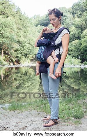 Portrait of young woman carrying baby daughter in sling on riverbank View Large Photo Image Stock Photo - Portrait of young woman carrying baby daughter in sling on riverbank. Fotosearch