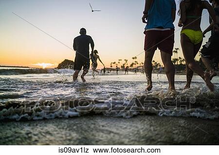 Rear view of adult friends running in sea at sunset, Newport Beach, California, USA View Large Photo Image Stock Photo - Rear view of adult friends running in sea at sunset, Newport Beach, California, USA. Fotosearch