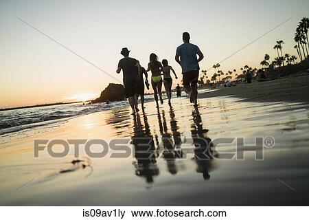 Rear view of adult friends running on beach at sunset, Newport Beach, California, USA View Large Photo Image Stock Photo - Rear view of adult friends running on beach at sunset, Newport Beach, California, USA. Fotosearch