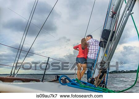 Stock Photo - Rear view of couple on bow of boat kissing. Fotosearch