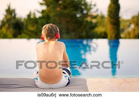 Rear view of teenage boy wearing headphones sitting at infinity pool View Large Photo Image Stock Image - Rear view of teenage boy wearing headphones sitting at infinity pool. Fotosearch