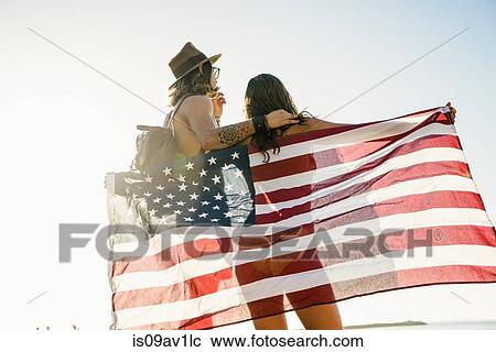 Rear view of young couple wrapped in American flag on Newport Beach, California, USA View Large Photo Image Stock Image - Rear view of young couple wrapped in American flag on Newport Beach, California, USA. Fotosearch