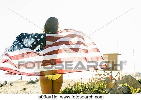 Rear view of young woman wrapped in American flag on Newport Beach, California, USA View Large Photo Image Stock Image - Rear view of young woman wrapped in American flag on Newport Beach, California, USA. Fotosearch