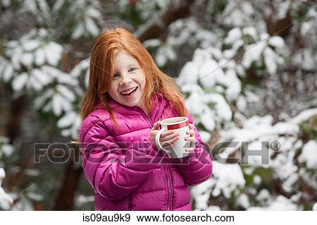 Red haired girl in front of snow covered trees, wearing pink padded coat holding mug looking away smiling View Large Photo Image Stock Photo - Red haired girl in front of snow covered trees, wearing pink padded coat holding mug looking away smiling. Fotosearch